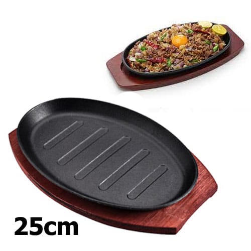 Cast iron hot sizzling plate on wooden tray